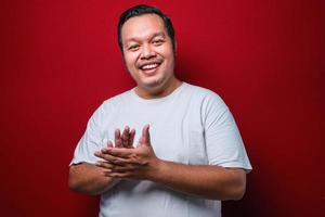 Young handsome man wearing white t-shirt clapping and applauding happy and joyful, smiling proud hands together photo