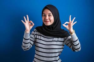 Portrait of happy smiling Asian muslim woman shows OK finger sign gesture photo