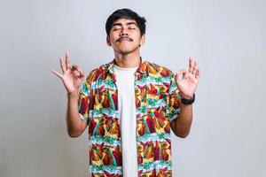 Young indian man wearing casual shirt relax and smiling with eyes closed doing meditation gesture with fingers photo