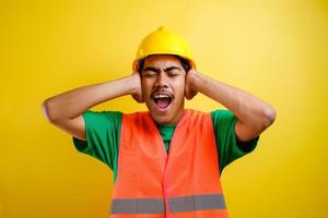 Worker wearing security helmet covering ears with fingers with annoyed expression photo