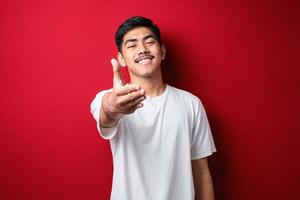 Man smiling friendly offering handshake as greeting and welcoming over red background. successful business. photo