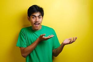 hombre asiático guapo sonriente señalando con el dedo a la mano abierta vacía foto