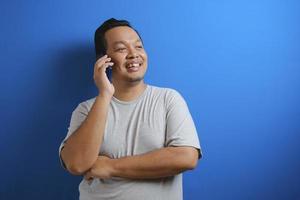 photo of a fat asian man wearing a gray shirt smiling while receiving a phone