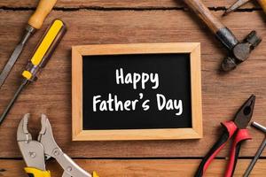 Happy Fathers Day text with side border of tools and ties on a rustic wood background photo