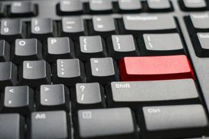 vista de cerca de un teclado de computadora portátil con un botón rojo en la mesa blanca de la oficina foto