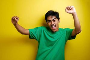 hombre asiático con camiseta verde sonriendo y bailando alegremente foto