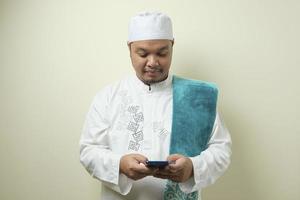 gordo musulmán asiático accediendo a su teléfono inteligente foto