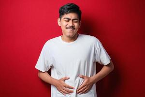 Hombre asiático Waring camiseta blanca diarrea problemas de salud sostenga su vientre foto
