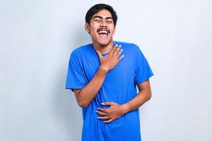 Asian boy smiling and laughing hard out loud because funny crazy joke with hands on body. photo