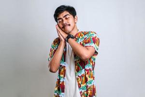 Asian man sleeping tired dreaming and posing with hands together while smiling with closed eyes photo