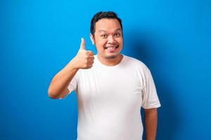 joven hombre guapo con pantalones casual sobre fondo rojo aprobando hacer un gesto positivo con la mano, pulgares arriba sonriendo y feliz por el éxito. gesto ganador. foto