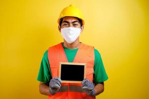 retrato de un trabajador asiático con una máscara protectora sosteniendo una pequeña pizarra foto