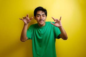 hombre asiático con camiseta verde sonriendo y bailando alegremente foto