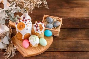 Festive cakes with white glaze, nuts and raisins with Easter eggs on the festive table photo