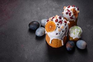 Festive cakes with white glaze, nuts and raisins with Easter eggs on the festive table photo