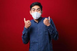 Asian college student man thumb up and wearing masks to prevent the spread of Corona virus while back to school. photo