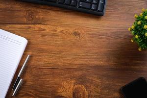 Wooden table with notebook, magnifying glass, pen, decorative plants photo