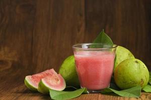 guava juice is served on a wooden background photo