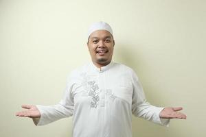 Portrait of Asian young muslim man smiling and pointing to presenting something on his side photo