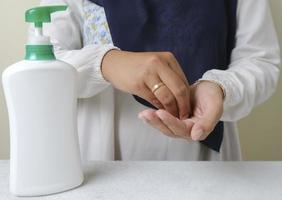 Washing hands by alcohol sanitizers or alcohol gel from pump bottle photo