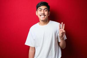 Handsome young man wearing casual clothes showing and pointing up with fingers number three while smiling confident and happy photo