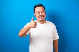 joven hombre guapo con pantalones casual sobre fondo rojo aprobando hacer un gesto positivo con la mano, pulgares arriba sonriendo y feliz por el éxito. gesto ganador. foto