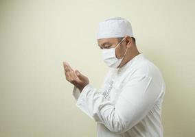 Asian Muslim man wearing mask praying photo