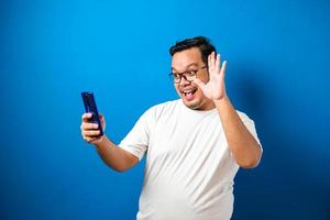 Studio portrait of a young east asian man making a video call and take selfie photo