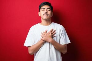 Handsome young man wearing casual clothes smiling with hands on chest with closed eyes and grateful gesture on face. health concept. photo