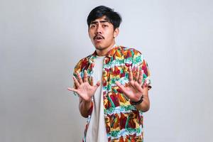 sian man moving away hands palms showing refusal and denial with afraid and disgusting expression photo