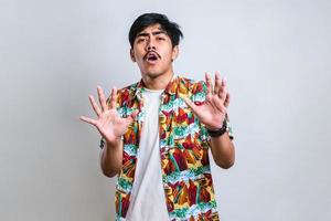 sian man moving away hands palms showing refusal and denial with afraid and disgusting expression photo