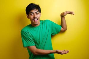 Smiling handsome Asian man pointing finger to empty open hand photo