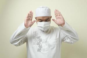 Asian Muslim man wearing mask praying photo