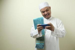 Fat Asian muslim man accessing his smart phone photo