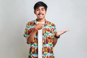 asian man with a big smile on face, pointing with hand finger to the side looking at the camera. photo
