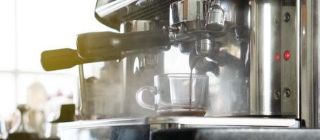 Close up picture of coffee maker machine brewing expresso into a cup in the restaurant. barista and coffee shop concept photo