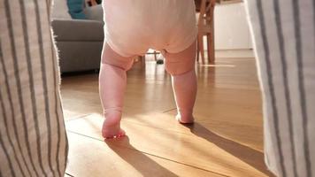mutter bringt dem kleinen baby bei, zu hause zu laufen - winzige beine auf dem boden video