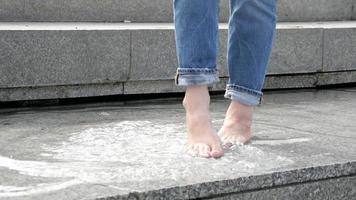 mujer descalza chica piernas jugar con el agua de la fuente de la calle de la ciudad video