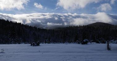 time-lapse van wolken die over de bergtop stromen op een zonnige winterdag. rustig en bevredigend moment. filmische opname van winterlandschap. vakantie in de bergen met sneeuw. video