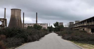 usina nuclear desativada. fábrica abandonada em um dia nublado. sentimento sombrio e apocalíptico. ambiente destruído. lixo nuclear. sobras industriais. video