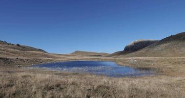 Beautiful seasonal lake in the mountains on a sunny autumn day. Natural and wonderful yellow and blue colors. Tranquil holiday feeling. Relaxing and calm. Nurture yourself in nature. video