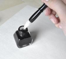 ink bottle with brush in hand for drawing on white photo