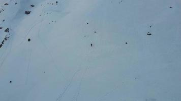 Aerial, drone view of solo mountaineer walking, hiking on a winter day to reach the mountain peak. Traveling and connecting with nature. Reaching for the mountain summit. Walking on deep snow. video