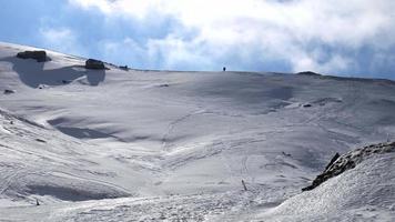 Solo mountaineer walking, hiking on a winter sunny day to reach the mountain peak. Wind and clouds are passing in the sky. Traveling and connecting with nature. video