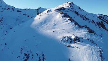 vista aérea, drone de alpinista solo caminhando, caminhando em um dia ensolarado de inverno para chegar ao pico da montanha. viajar e se conectar com a natureza. alcançando o cume da montanha. andando na neve profunda. video