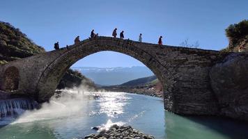 pont de kadiut, benje, permet, albanie, 1er janvier 2022. personnes traversant un pont de pierre par une journée ensoleillée d'hiver. vacances d'hiver. vapeur provenant des thermes. préparer la médiation. calme et détente.