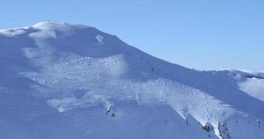 alpinistes marchant, faisant de la randonnée par une journée ensoleillée d'hiver pour atteindre le sommet de la montagne. voyager et se connecter avec la nature. expédition pour atteindre le sommet de la montagne, en haut. marcher sur la neige profonde. video