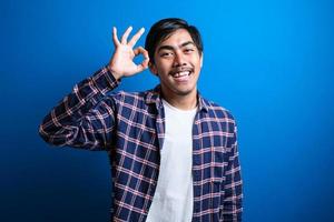 Happy asian man smiles looked at camera against blue background photo