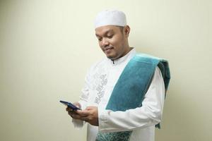 Fat Asian muslim man accessing his smart phone photo