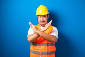 Fat asian workman wearing orange safety vest and yellow helmet making stop gesture photo